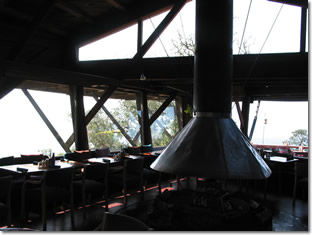 Photograph of the benches and dining tables, and the hooded fireplace inside Nepenthe restaurant in Big Sur, California. Image copyright © Philip W. Tyo 2008
